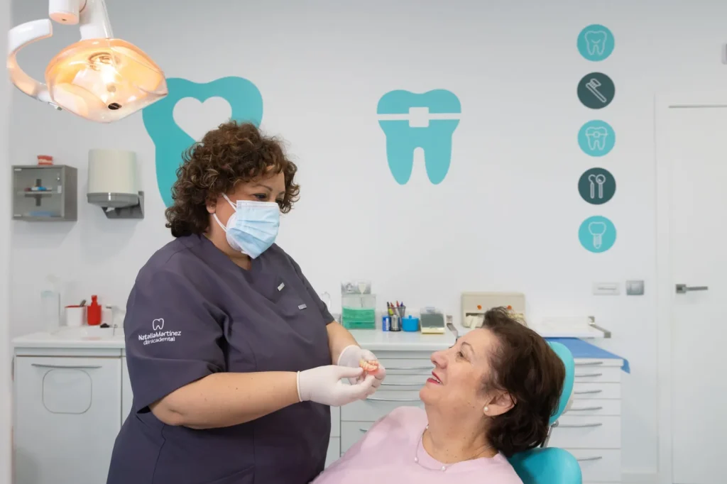 Profesional mostrando la prótesis dental removible a una paciente en la clínica de Córdoba